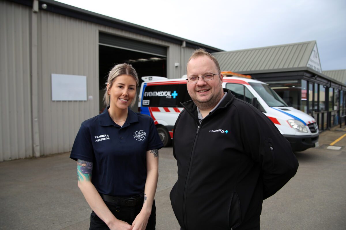 APC student and trainer standing in front of an ambulance